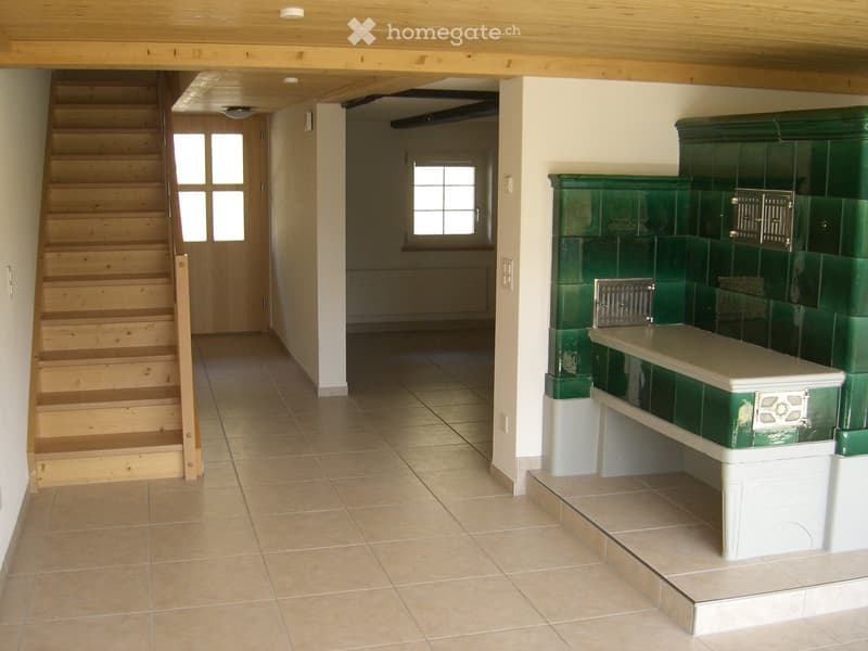 Hallway with wooden staircase, tiled floor, and green fireplace with white mantel.