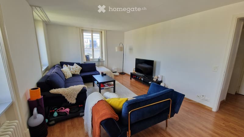 Modern living room with a dark blue sectional sofa, armchair, coffee table, TV, floor lamp, and decorative items.