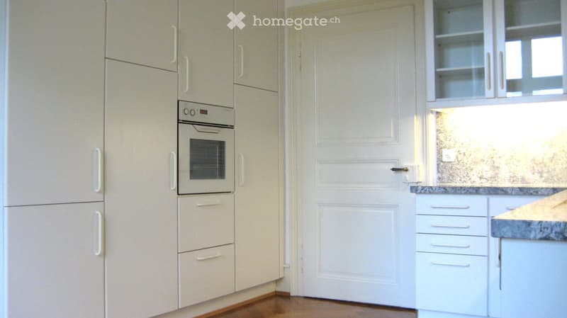 Modern kitchen with white cabinets, built-in oven, and granite countertop.