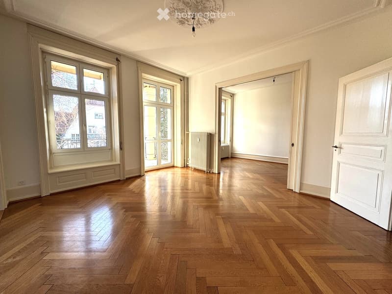 Empty room with wooden flooring, large windows, and white walls. No furniture or equipment present.