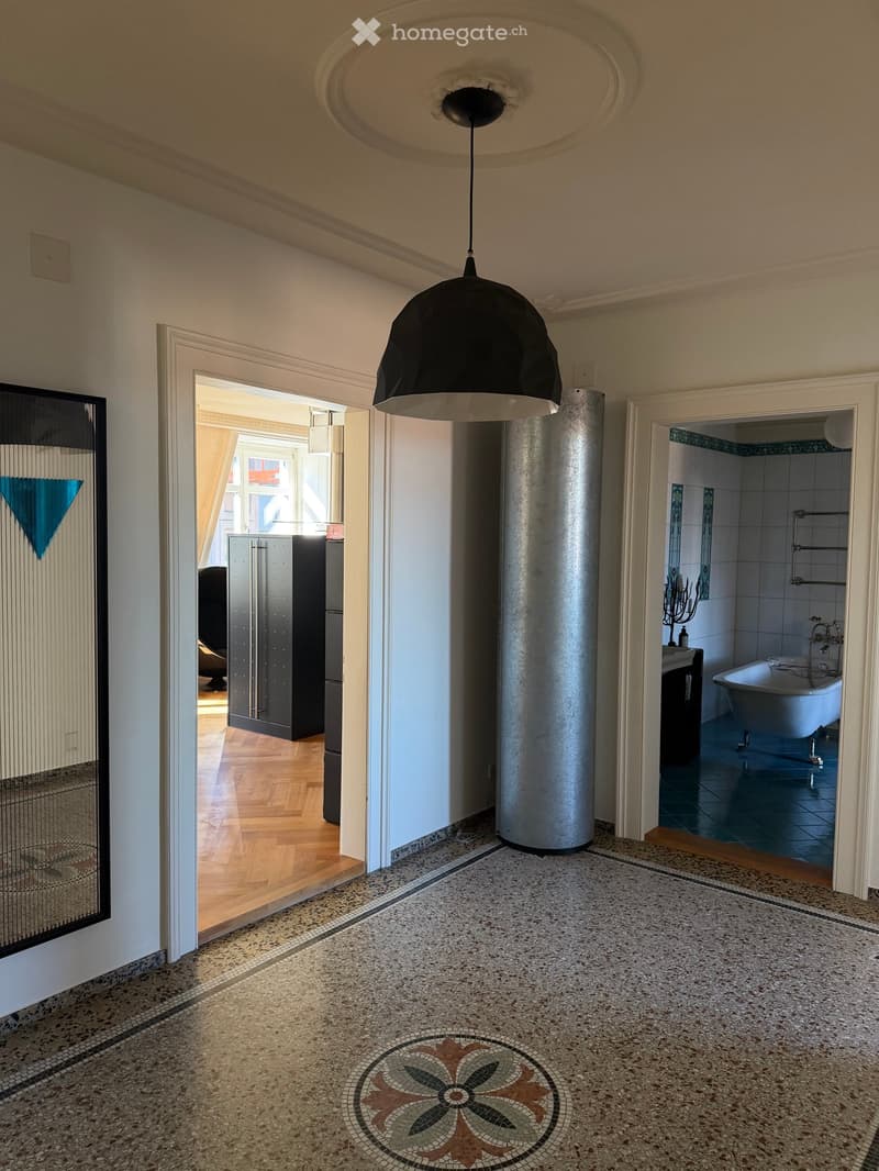 Elegant hallway with a decorative mosaic floor, pendant light, and views into adjacent rooms including a bathroom and a bedroom.