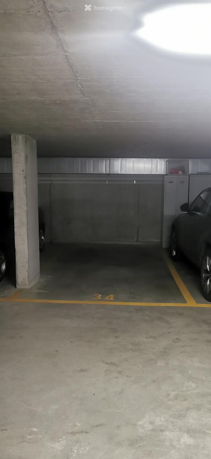 Other. Underground parking space with concrete floors and walls, marked parking spots, and a parked car visible in the background.