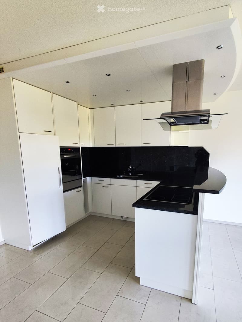 Modern kitchen with white cabinets, black countertops, a built-in stove, refrigerator, and a central island with a sink.