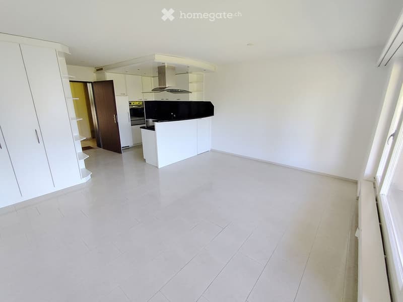 Empty kitchen with white cabinets, a countertop, and a tiled floor. No appliances or furniture are present.