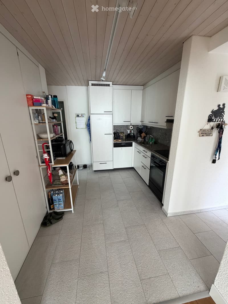 Modern kitchen with white cabinets, tiled floor, and various appliances including a refrigerator, oven, microwave, and sink.