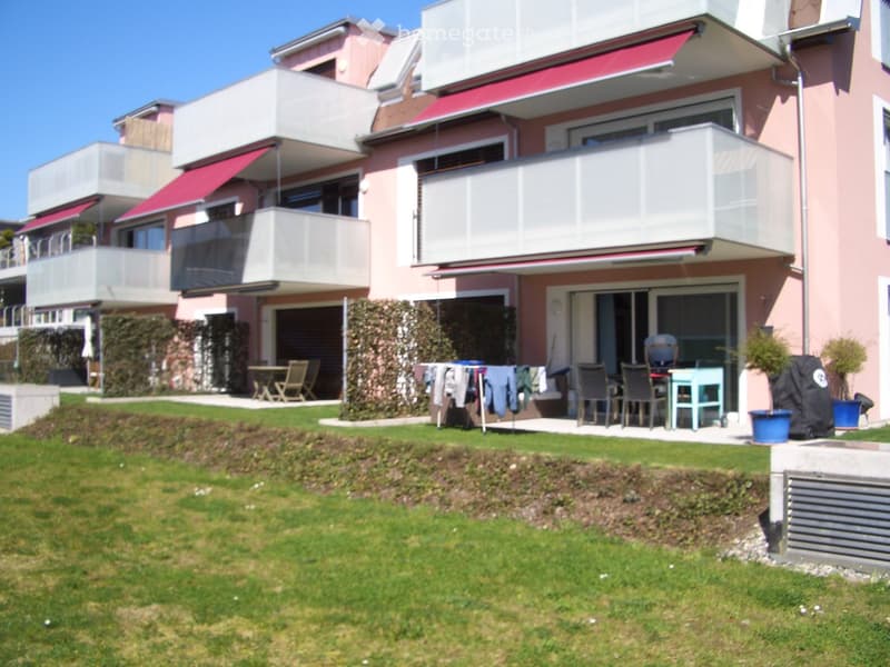 Modern two-story house with balconies, outdoor seating area, and well-maintained lawn.