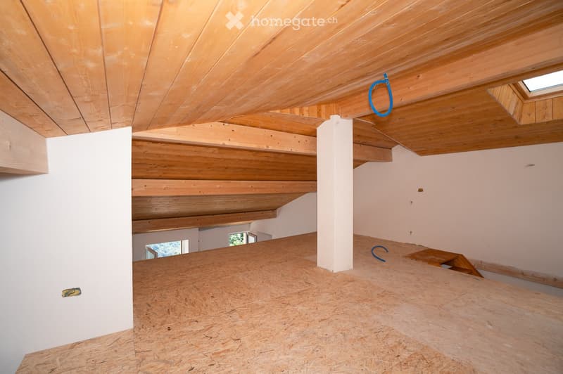 Empty attic space with wooden beams, exposed wooden ceiling, and unfinished wooden floor. No furniture or equipment present.