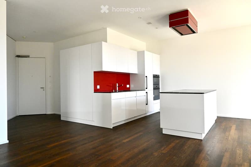 Modern kitchen with white cabinets, a red backsplash, a central island, and a dark wooden floor.