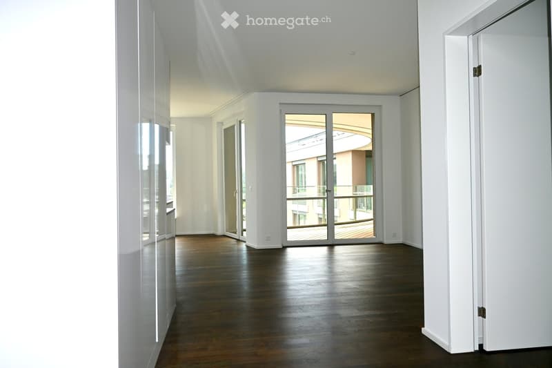 Empty room with wooden flooring, white walls, and large glass doors leading to a balcony.