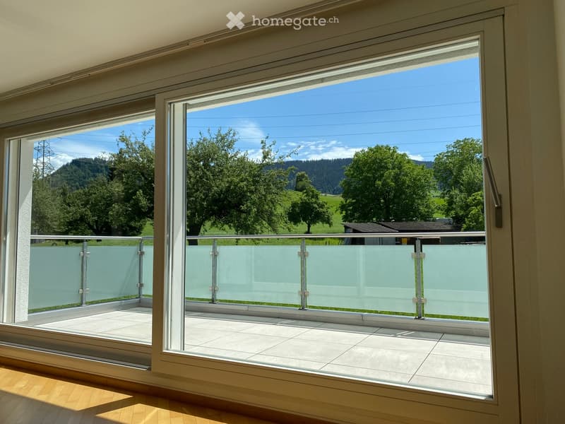 Large balcony with glass railing, tiled floor, and scenic mountain view.