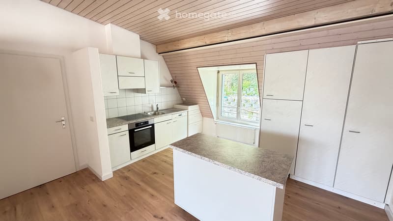 Bright kitchen with white cabinets, granite countertop, sink, and oven. Wooden flooring and large window provide natural light.