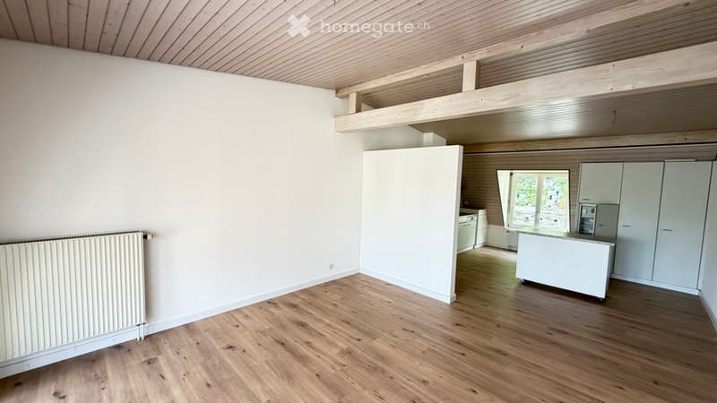 Empty room with wooden flooring, white walls, and exposed wooden beams on the ceiling. No furniture or equipment is present.