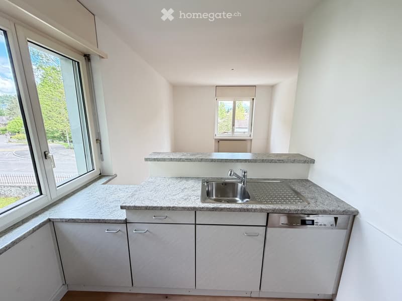 Modern kitchen with white cabinets, granite countertops, and a stainless steel sink and dishwasher.