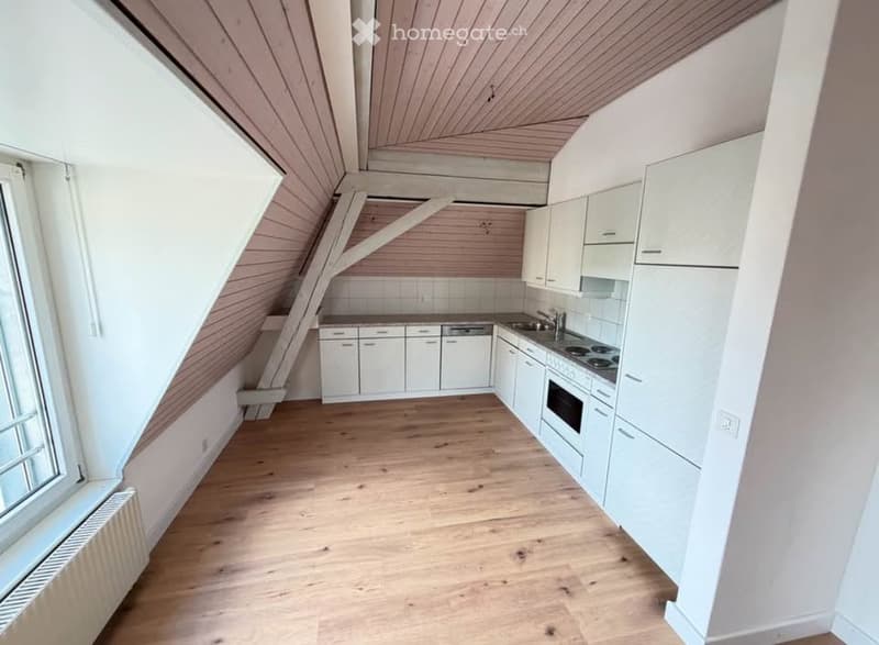 Bright kitchen with white cabinets, wooden flooring, and modern appliances including a stove, oven, and sink.