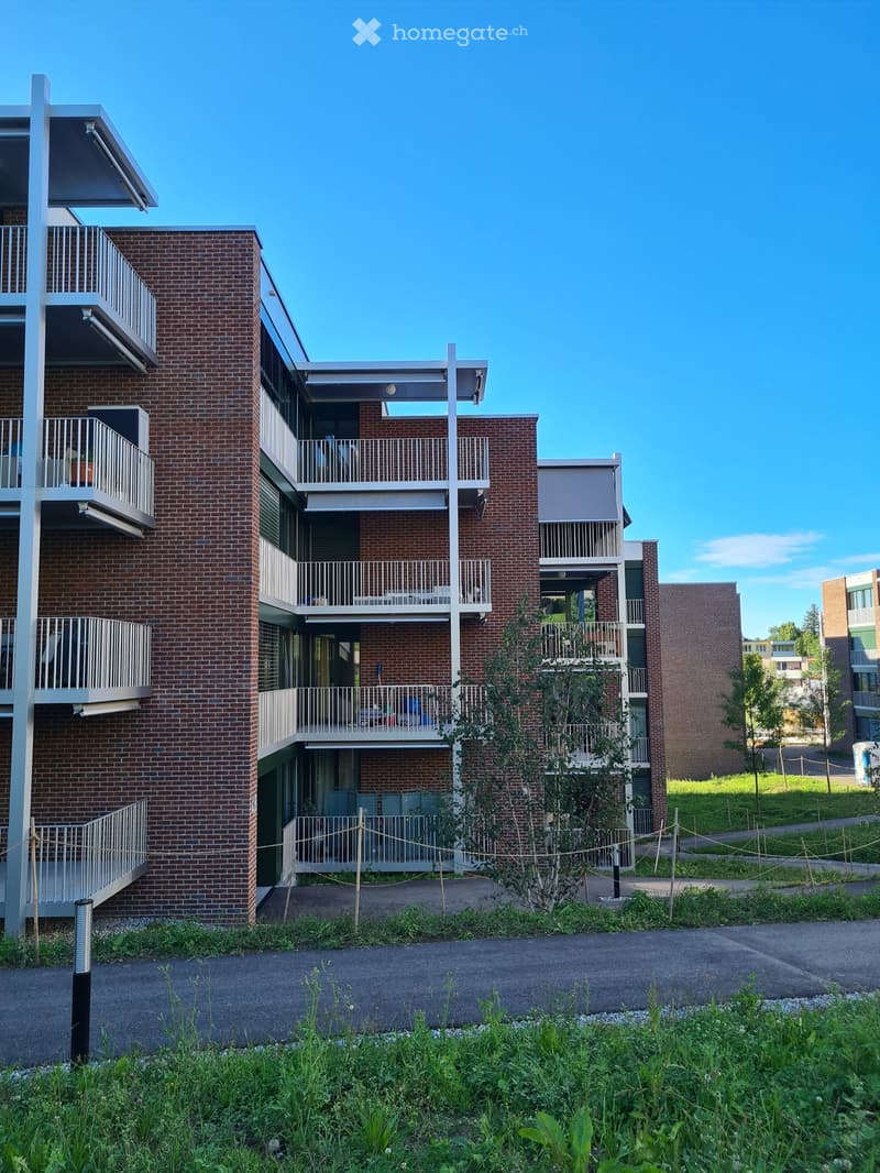 3-story brick building with multiple balconies and a well-manicured lawn