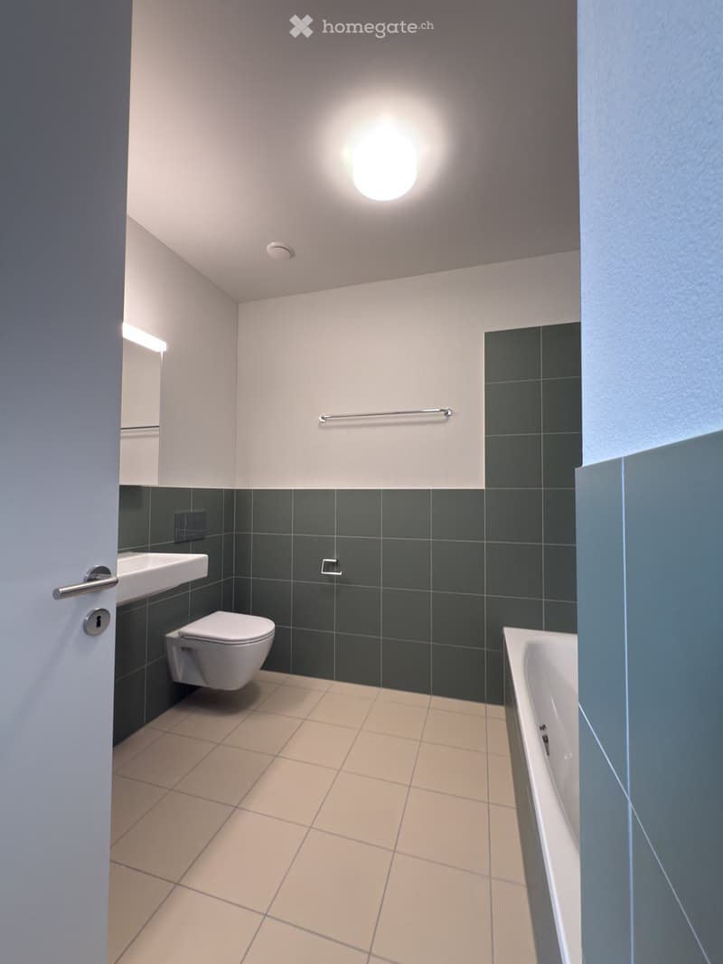 modern bathroom with white tile, white bathtub, white sink, and white toilet, with mirror