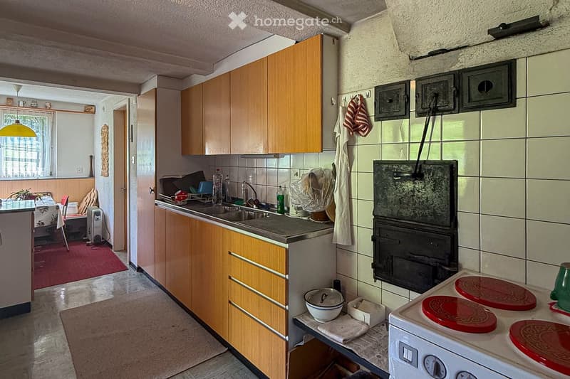 kitchen with wooden cabinets, stainless steel sink, gas stove, white tiled wall, tiled floor