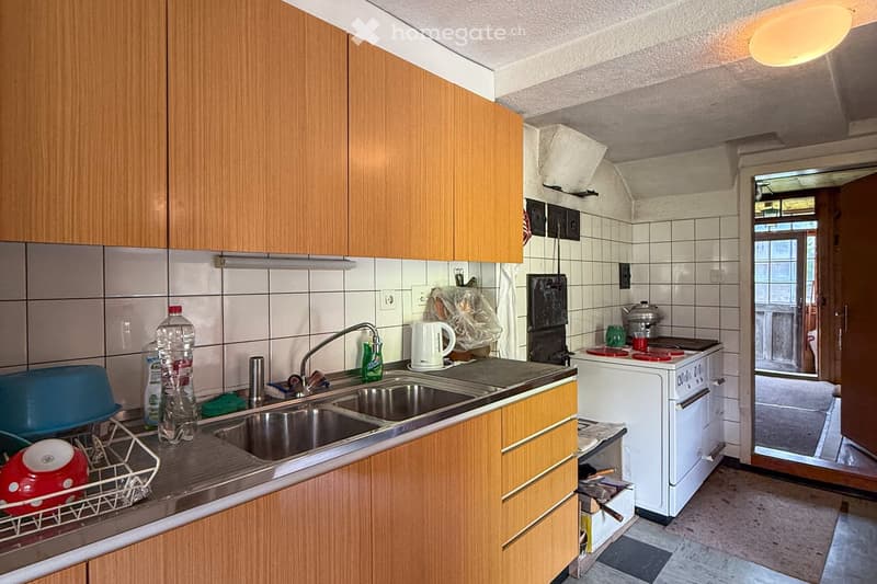 wooden cabinets, countertop, sink, stove, kettle, dish drainer
