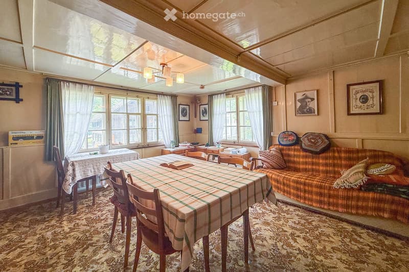 Dining room with a table and chairs, couch with pillows, two picture frames, chandelier