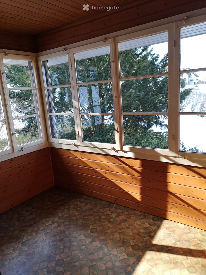 Large windows, wooden walls, tile flooring, view of trees and water
