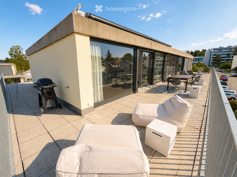 Balcony / Terrace. Modern rooftop terrace with tiled flooring, large glass sliding doors, white outdoor seating including sofas and a table with chairs, and a grill on the left side.
