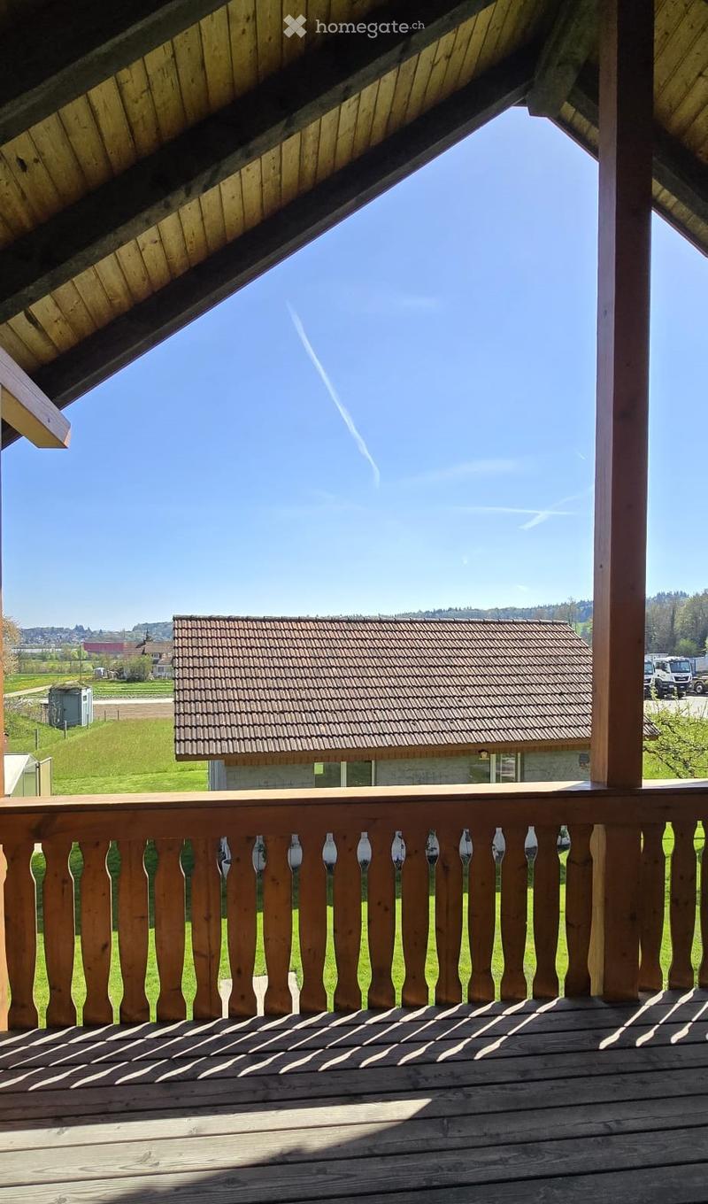 wooden balcony, wooden railing, view of a house and a field