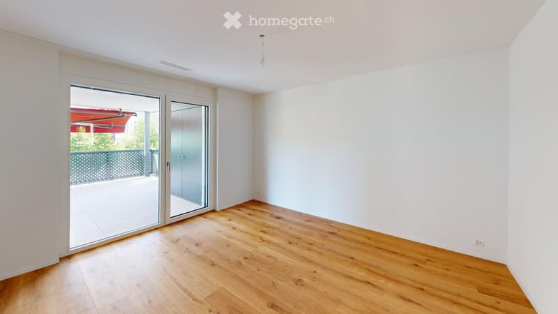 Empty room with wooden flooring, white walls, and large sliding glass doors leading to a balcony or terrace.