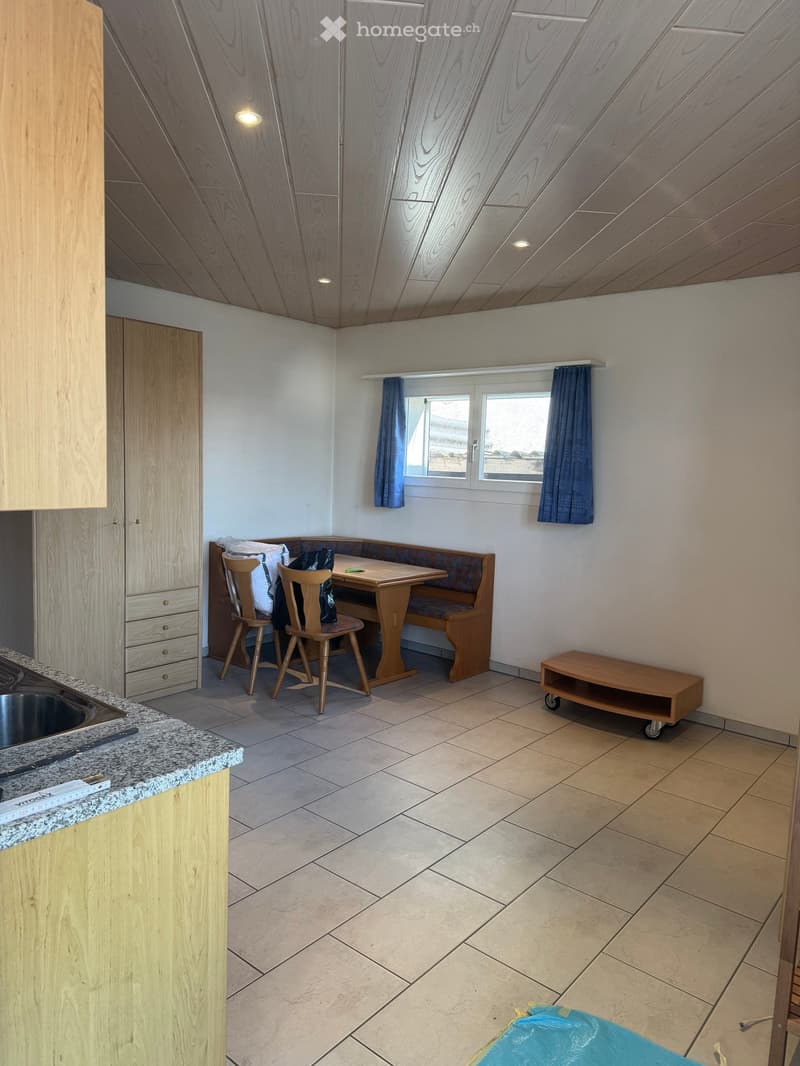 kitchen with dining area, wooden furniture, white walls, tiled floor, window with blue curtains