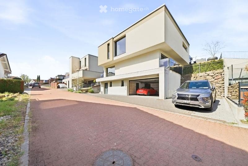Modern two-story house with a garage and parking area, featuring clean lines and contemporary design.