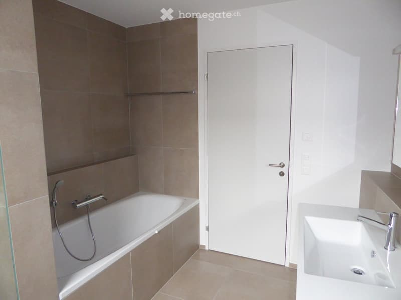 Bathroom. Modern bathroom with a bathtub, a sink, and a glass shower enclosure. The walls are tiled in neutral tones, and the floor is tiled in beige.