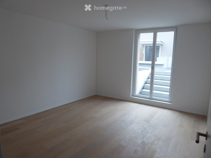 Unfurnished Room. Empty room with wooden flooring and white walls, featuring a large sliding glass door leading to a balcony area.