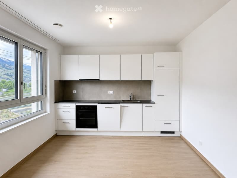 Modern kitchen with white cabinets, black countertop, built-in oven, and large windows offering a scenic view.