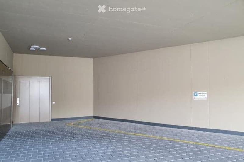 parking lot, grey brick, 2 white doors, white walls, one marked parking spot, elevator