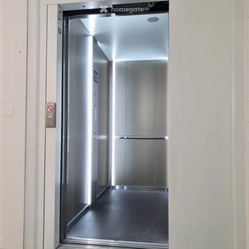 Stainless steel interior with illuminated wall and floor, door with handle and window, buttons and emergency phone on the wall