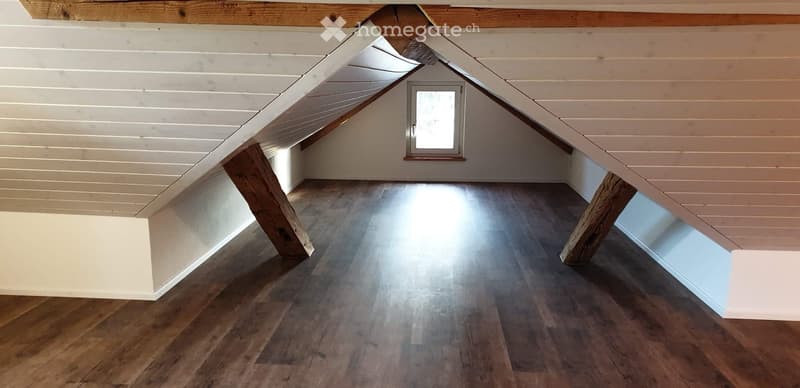 Unfurnished Room. Empty attic space with wooden floors, white paneled ceiling, and a small window letting in natural light.