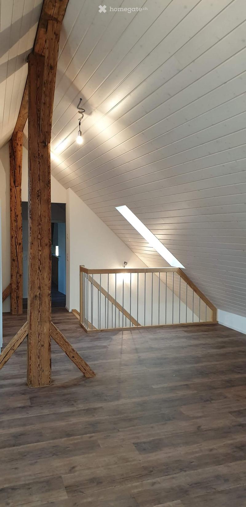 Corridor / Hallway. Spacious hallway with wooden floors, exposed wooden beams, and a modern staircase with metal railings. The ceiling features white paneling and recessed lighting.