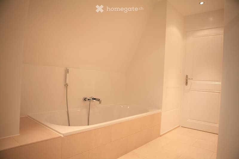 Bathtub, shower head, tiled walls, white door, beige tiles
