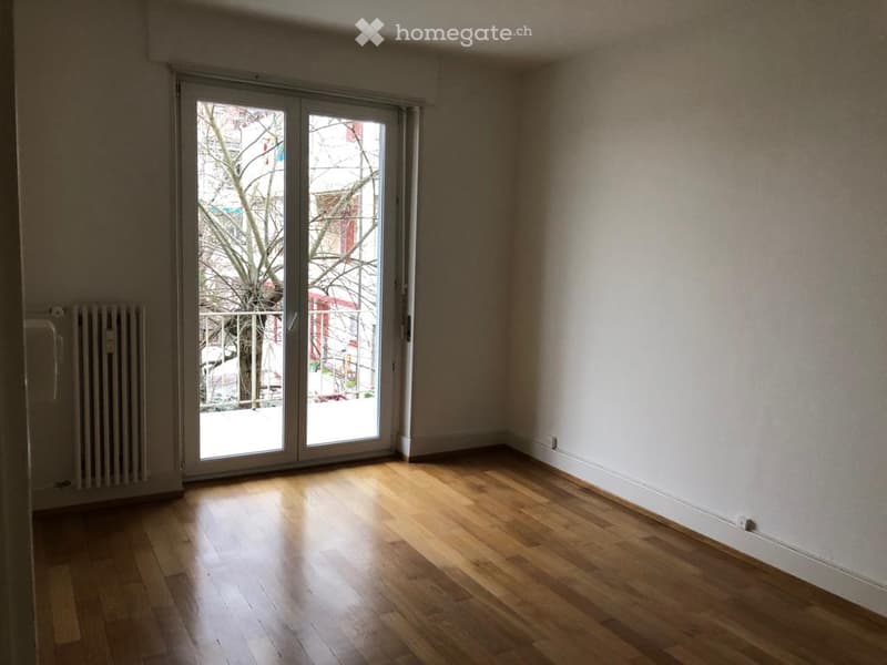 empty room, hardwood floors, white walls, sliding glass doors to a balcony, white radiator