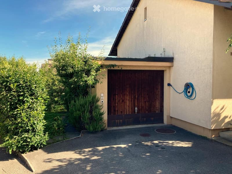 Exterior of a house with a wooden garage door and a driveway.
