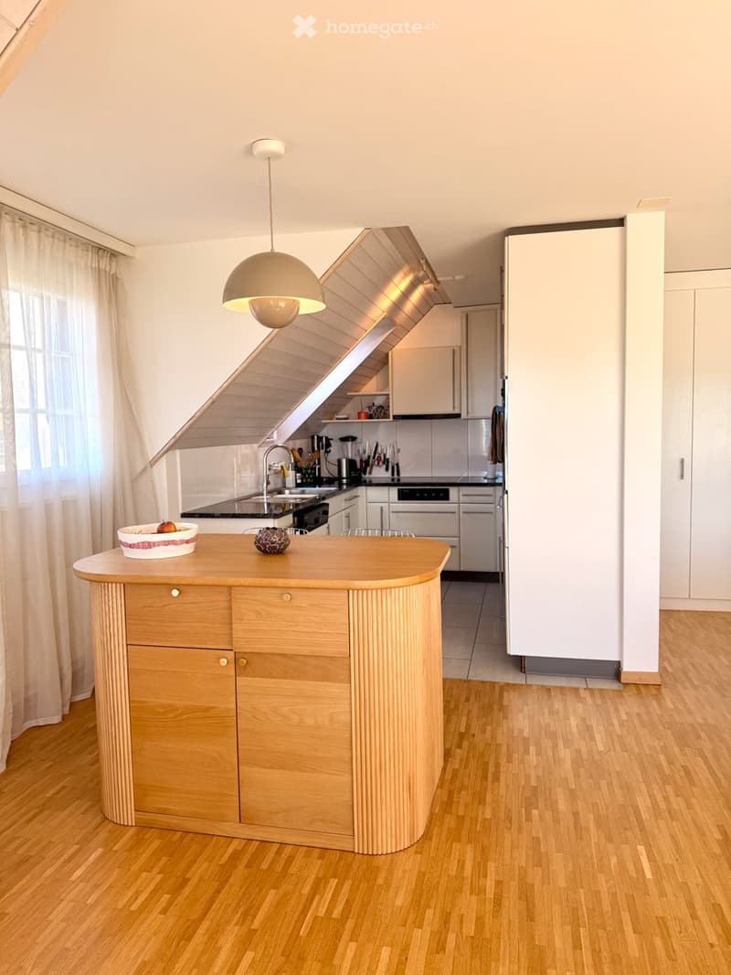 Modern kitchen with a wooden island, white cabinets, stainless steel appliances, and a pendant light fixture.