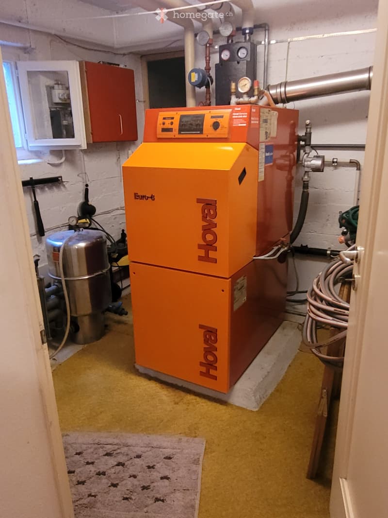 Utility room with a large orange and red Hoval boiler unit, a silver water cylinder, and a red cabinet.