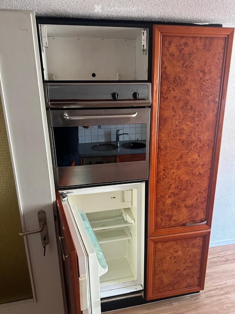Modern kitchen with stainless steel appliances, including an open refrigerator, oven, and sink, with wooden cabinetry.