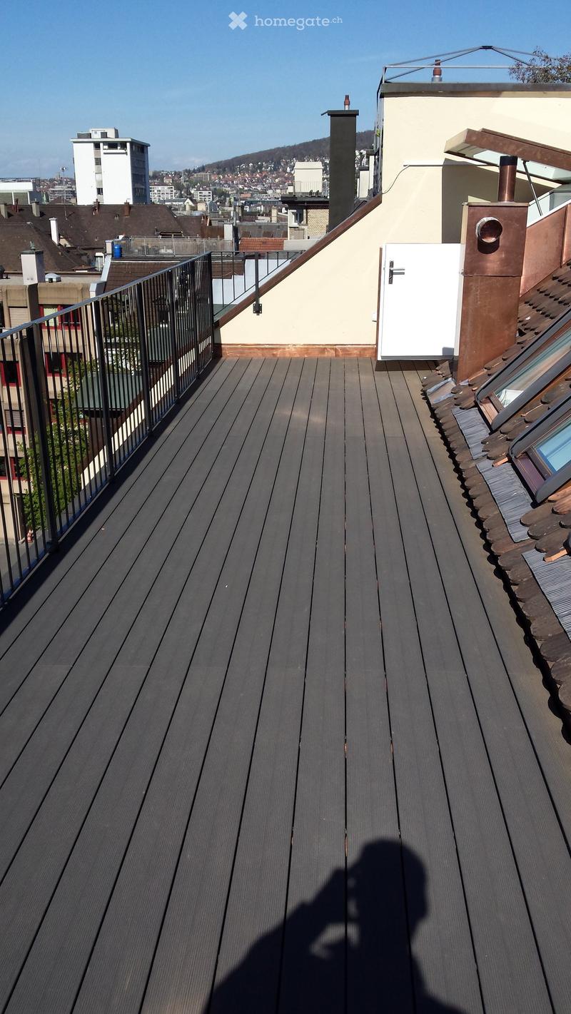 Roof terrace with wooden floor, metal railing, and a view of the city