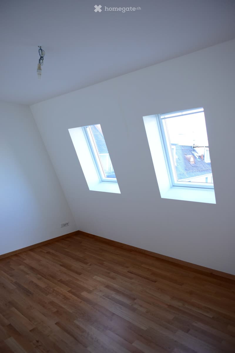 empty room, wooden floor, white walls, two windows, slanted ceiling