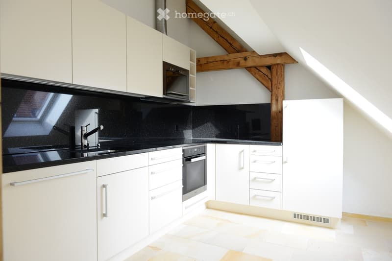 modern kitchen with white cabinets, black granite countertops, stainless steel appliances, wooden beams