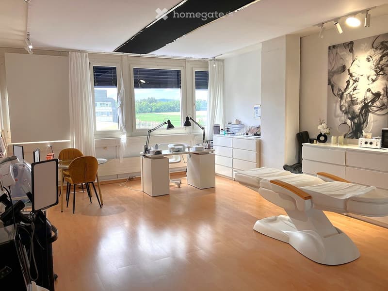Well-lit room with wooden flooring, large windows, and several treatment chairs arranged for clients.