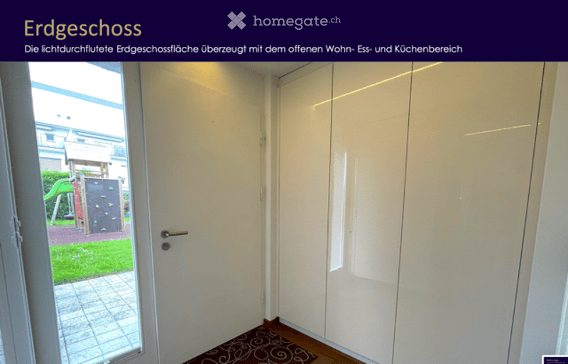 Empty room with white walls, wooden floor, white closet, and a small patterned rug near the door. The door leads to an outdoor area with a playground visible.
