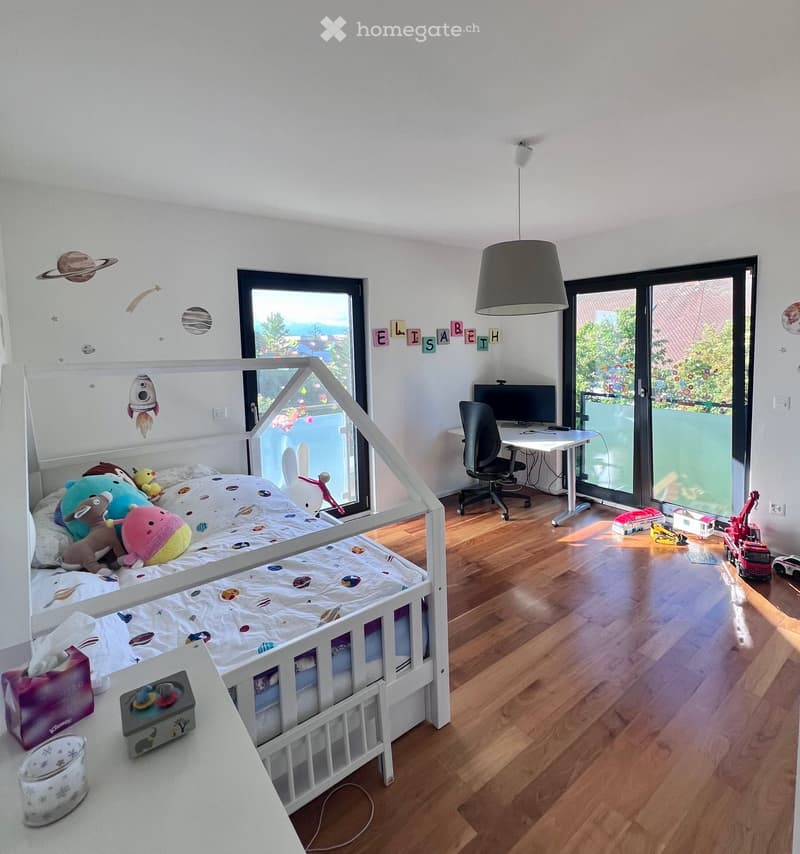 Bright, modern children's bedroom with a bunk bed, desk, and various toys. Features large windows with a view of greenery, a hanging lamp, and decorative wall elements.
