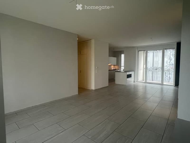 Empty room with tiled floor, white walls, and a sliding glass door leading to a balcony.