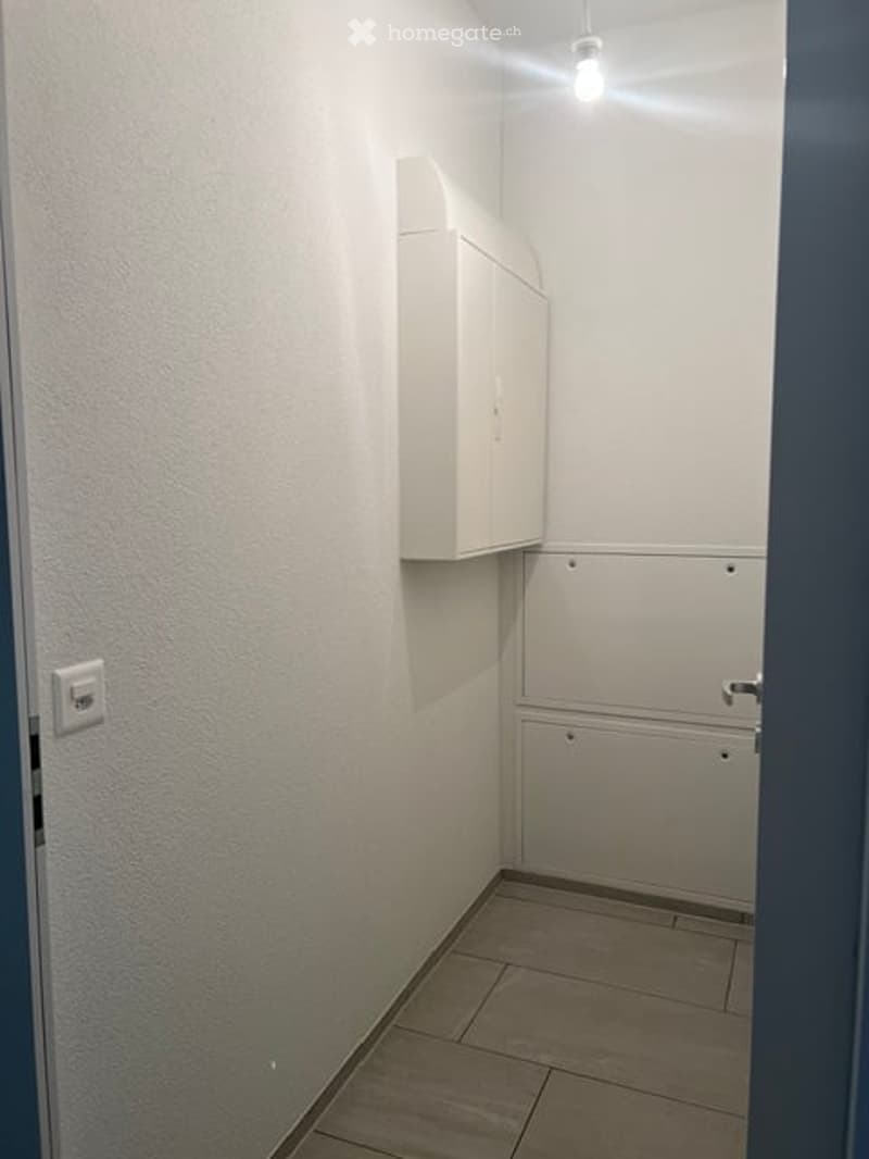Empty room with white walls, tiled floor, and a small cabinet mounted on the wall. No furniture or equipment is present.